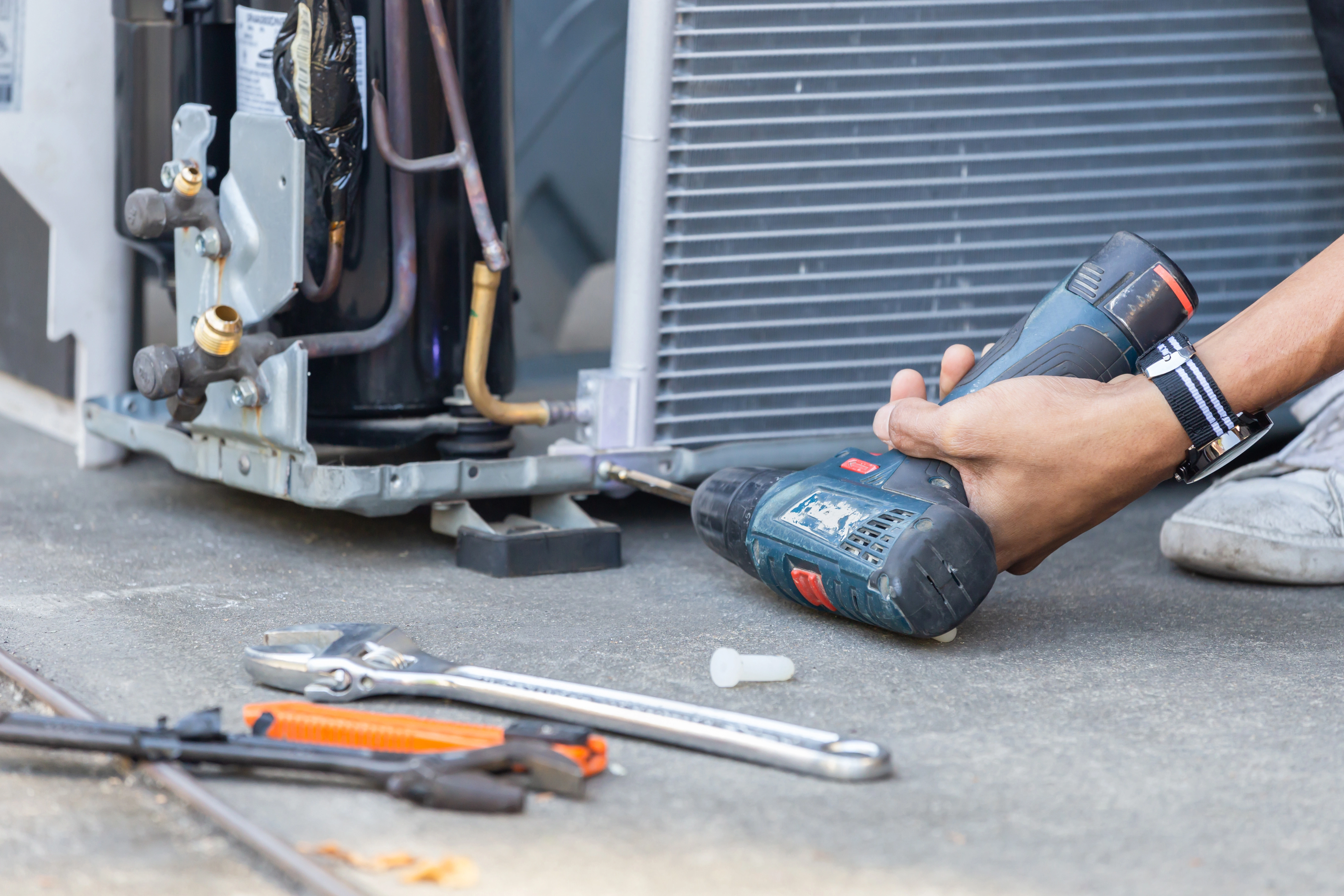 A technician cleans an AC compressor with a power drill as part of an AC tune-up in Nashville.